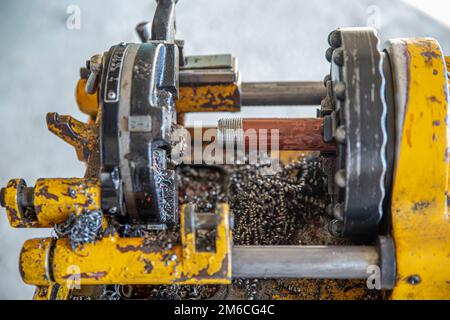 Abschrägmaschine für Eisenrohre. Techniker ist ein gerilltes Stahlrohr. Rohrnut zur Brandbekämpfung Installation einer Sprinkleranlage Arbeiter, der Eisenstangen schneidet. Stockfoto