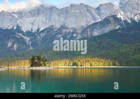 Wunderschöner, türkisfarbener Eibsee mit Blick auf das Wettersteingebirge und den von letzten Sonnenstrahlen beleuchteten Uferbereich Stockfoto