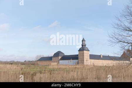 Hasselt. Limburg - Belgien. 01/24/2021 eine alte Burg am Ufer des Flusses. Landschaft - Schilf, blauer Himmel Stockfoto