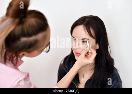 Make-up-Künstler malt Augenbrauen für ein junges Mädchen Stockfoto