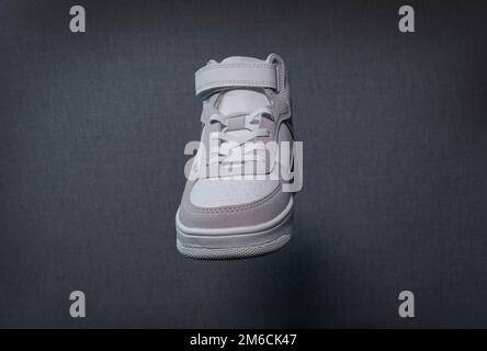 Weißer Sneaker. Frontteil. Auf grauem Hintergrund. Nahaufnahme, Textur Stockfoto