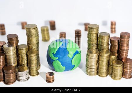 Viele Münzen auf dem weißen Tisch mit dem Erdmodell. Stockfoto