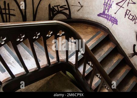 Graffiti an den Wänden einer alten Holztreppe in einem verlassenen Haus. Stockfoto