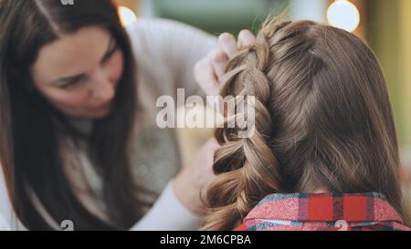 Die Make-up-Künstlerin macht einen Zopf für das Model. Stockfoto