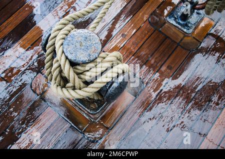 Poller mit einem Seil auf der Holzterrasse der ein Segelschiff, close-up Stockfoto