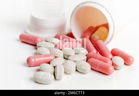 Pillen und Kapseln in einem Glas auf weißem Hintergrund Stockfoto