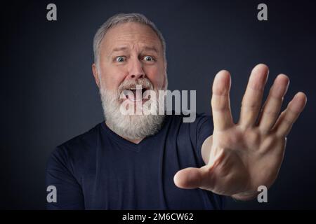 Panischer alter Mann mit gestreckter Hand nach vorne Stockfoto