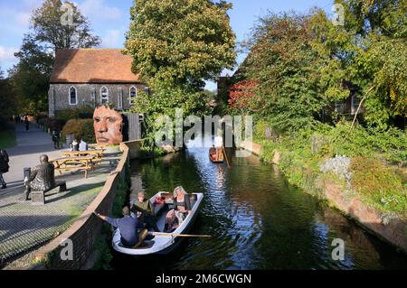 Kahnboote auf dem Great Stour River oder River Stour, Canterbury, Kent, England, Großbritannien. Schott-Masken-Skulptur vor dem Blackfriars-Kloster. Stockfoto