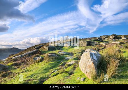 Schafe, die auf schrägem felsigem Gelände in der Nähe von Bamford Edge im Peak District National Park, Derbyshire, England, Großbritannien, unterwegs sind Stockfoto