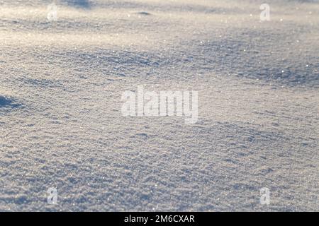 Hintergrund von weißem Schnee, der in der Sonne glitzert. Geringe Schärfentiefe Stockfoto