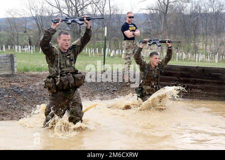 2. LT. Scott Messner (links), zugewiesen zu Bravo Company, 1. Bataillon, 109. Infanterieregiment, 2. Infanterie-Brigade-Kampfteam, 28. Infanterie-Division und 2. LT. Zachary Biveri (rechts), zugewiesen zu Bravo Company, 1. Bataillon, 111. Infanterie-Regiment, 56. Stryker-Brigade-Kampfteam, 28. ID Halten Sie ihre Waffen in der Luft, während sie während eines Ranger Sapper Assessment Program am 23. April in Fort Indiantown Gap, Pa, in eine Wassergrube stürmen Messner und Biveri führten dann verschiedene Ranger-Ausbildungsaufgaben durch, während Staff Sgt. Erich Friedlein, ein Kurskader, sie weiter durch die Indiv unterrichtete Stockfoto