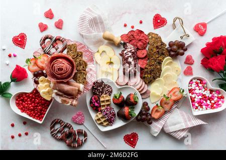 Auswahl an Wurstwaren zum Valentinstag, darunter Aufschnitt, Käse und Süßigkeiten. Stockfoto