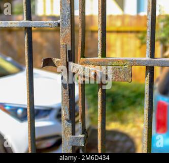 Am 31. Oktober 2020 in New Orleans, Louisiana, USA, befindet sich das antike, eingerastete Metalltor mit geparkten Autos und Holzzaun im Hintergrund Stockfoto