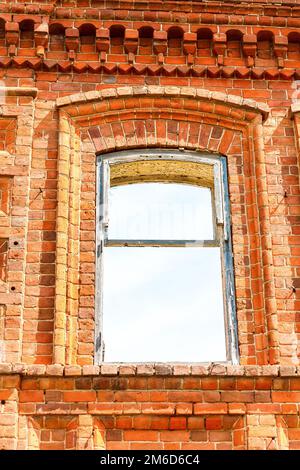 Ein großes, altes Haus aus rotem Backstein vor einem blauen Himmel mit weißen Wolken. Stockfoto
