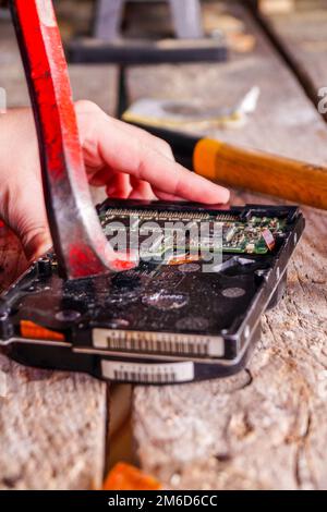 Ein Mann zerbricht einen Computer mit Schlosser. Stockfoto