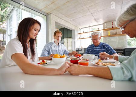 Es gibt immer etwas, wofür man dankbar sein kann. Eine Familie, die das Tischgebet spricht, bevor sie ihr Essen isst. Stockfoto