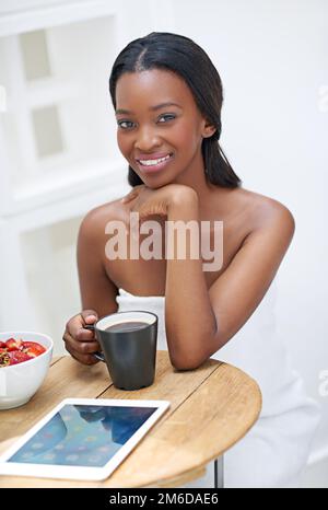 Alles, was ich brauche, um den Tag richtig zu beginnen. Eine junge Frau, die Erdbeeren isst. Stockfoto