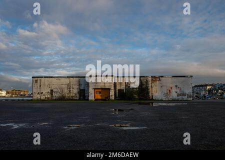 Saint-Nazaire, Loire Atlantique, Frankreich. 25. Dezember 2022. Ein altes geschlossenes Gebäude im Hafen von Saint-Nazaire (Loire-Atlantique) Trotz der optimistischen Ankündigungen der französischen Regierung, die für 2023 ein Wachstum von 1% erwartet, dürfte sich die Wirtschaftstätigkeit nach Ansicht von Ökonomen in den kommenden Monaten verlangsamen. In Saint-Nazaire (Loire-Atlantique) verfügen die Unternehmen Airbus und Chantiers de l'Atlantique über ein ausreichend großes Auftragsbuch, um eine mögliche Rezession zu vermeiden. (Kreditbild: © Laurent Coust/SOPA Bilder über ZUMA Press Wire) Stockfoto