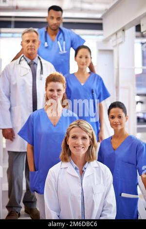 Sie wissen, was sie tun. Porträt eines vielfältigen Teams von Medizinern, die auf einer Treppe in einem Krankenhaus stehen. Stockfoto