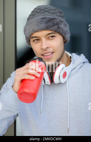 Lächelnder junger lateiner, der Wasser trinkt, im Porträtformat Wintersporttraining Fitness Stockfoto