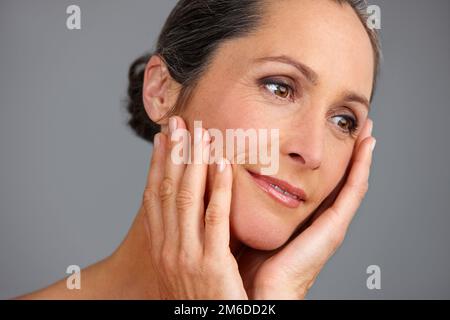 Zeitlose Schönheit. Studioaufnahme einer schönen, reifen Frau, die vor grauem Hintergrund posiert. Stockfoto