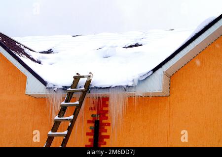 Auf einem Wohnhaus liegt viel Schnee und große Schneeverwehungen. Stockfoto