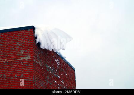 Auf einem Wohnhaus liegt viel Schnee und große Schneeverwehungen. Stockfoto