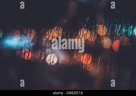 Ampel durch das Fenster in einer regnerischen Nacht Stockfoto