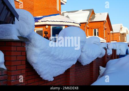 Auf einem Wohnhaus liegt viel Schnee und große Schneeverwehungen. Stockfoto