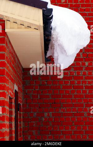 Auf einem Wohnhaus liegt viel Schnee und große Schneeverwehungen. Stockfoto