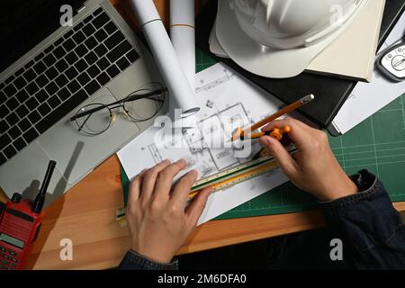 Ingenieur oder Architekt, der mit Bauplänen arbeitet und Entwicklungsdetails an der Workstation plant. Draufsicht Stockfoto