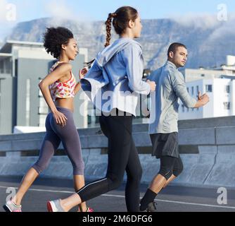 Das Joggingpaket. Eine Gruppe von Freunden, die zusammen durch die Stadt joggen. Stockfoto