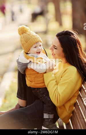 Junge Mutter und Baby sitzen auf einer Bank Stockfoto