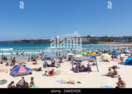 Überfüllter Bondi Beach im Sommer 2023, Leute sonnen sich und suchen Schatten unter schattigen Zelten, Sydney Beach, NSW, Australien Stockfoto