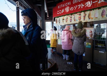 Otaru, Japan - 19. Dezember 2022: Touristen kaufen köstliches farbenfrohes Eis in der berühmten Eisdiele in Otaru Stockfoto