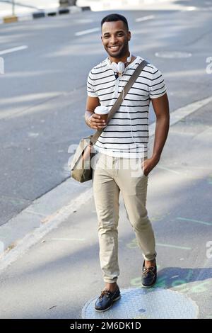 Moderner urbaner Stil. Ein gutaussehender, lässig gekleideter afroamerikanischer Geschäftsmann in der Stadt mit Kopfhörern um den Hals. Stockfoto