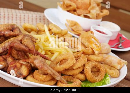 Verschließen Sie gebratene Zwiebelringe und Hähnchenflügel Stockfoto