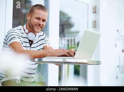 Das Gefühl der Selbstständigkeit ist ein Vorteil. Porträt eines gutaussehenden jungen Mannes, der draußen an einem Laptop arbeitet. Stockfoto