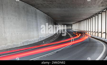 Rotes Rücklicht mit Langzeitbelichtung bei Fahrzeugen, die durch einen Tunnel fahren Stockfoto
