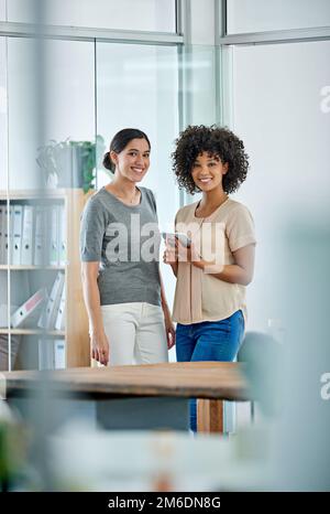 Selbstbewusste Kreative. Porträt von zwei Bürokollegen, die sich über ein digitales Tablet unterhalten. Stockfoto