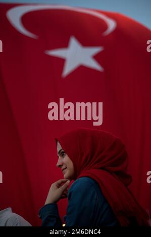 Türkische muslimische Frau mit rotem Kopftuch und türkischer Flagge, die an einer Regierungskonferenz teilnimmt Stockfoto