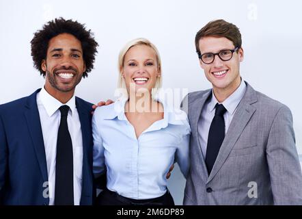 Positiv über unsere Leistung. Porträt von drei glücklichen Kollegen, die selbstbewusst in die Kamera lächeln. Stockfoto