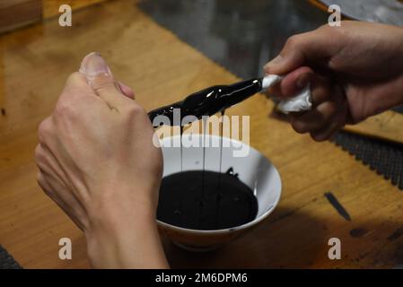 Filtration von japanischem Lackurushi zum Entfernen von Staubpartikeln – Vorbereitung von Rohmaterial zur Herstellung von luxuriösen und glänzenden traditionellen Lackartikeln Stockfoto