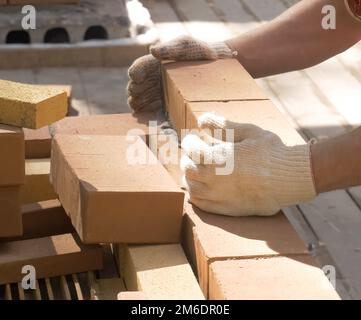 Ein Mann baut eine Mauer. Brick hat die Lösung aufgetragen. Bau eines Ziegelhauses. Stockfoto