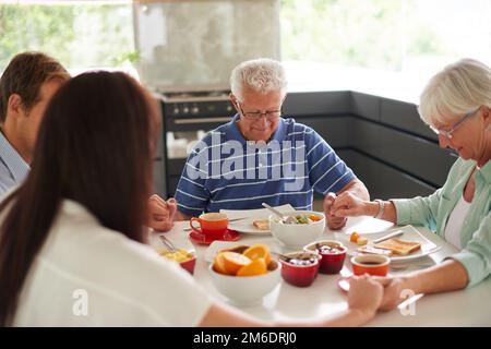 Sei dankbar für all die kleinen Dinge. Eine Familie, die ein Gebet spricht, bevor sie ihr Essen isst. Stockfoto