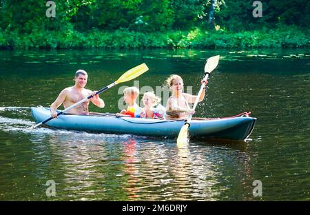 Eine junge Familie mit Sohn und Tochter fährt mit dem Kajak auf dem See. Stockfoto