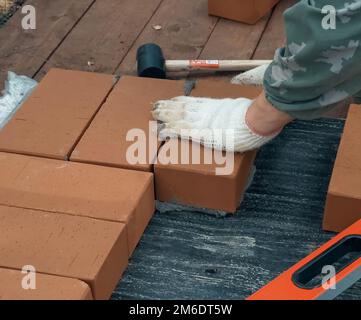 Ein Mann baut eine Mauer. Brick hat die Lösung aufgetragen. Bau eines Ziegelhauses. Stockfoto