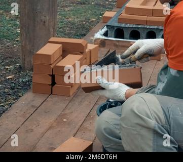 Ein Mann baut eine Mauer. Brick hat die Lösung aufgetragen. Bau eines Ziegelhauses. Stockfoto