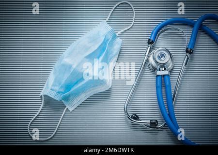 Einweg-Gesichtsmaske Stethoskop auf gestreiftem Hintergrund. Stockfoto