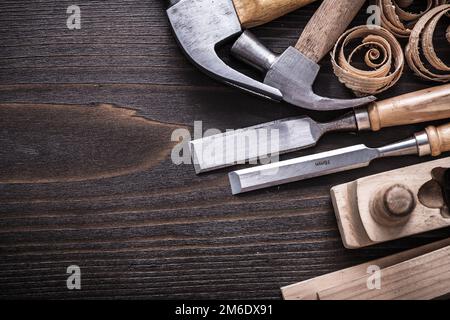 Horizontale Ausführung des Hobelhammers Metallmeißel Holzbolzen und gewellte Späne auf altem Holzbrettbaukonzept. Stockfoto